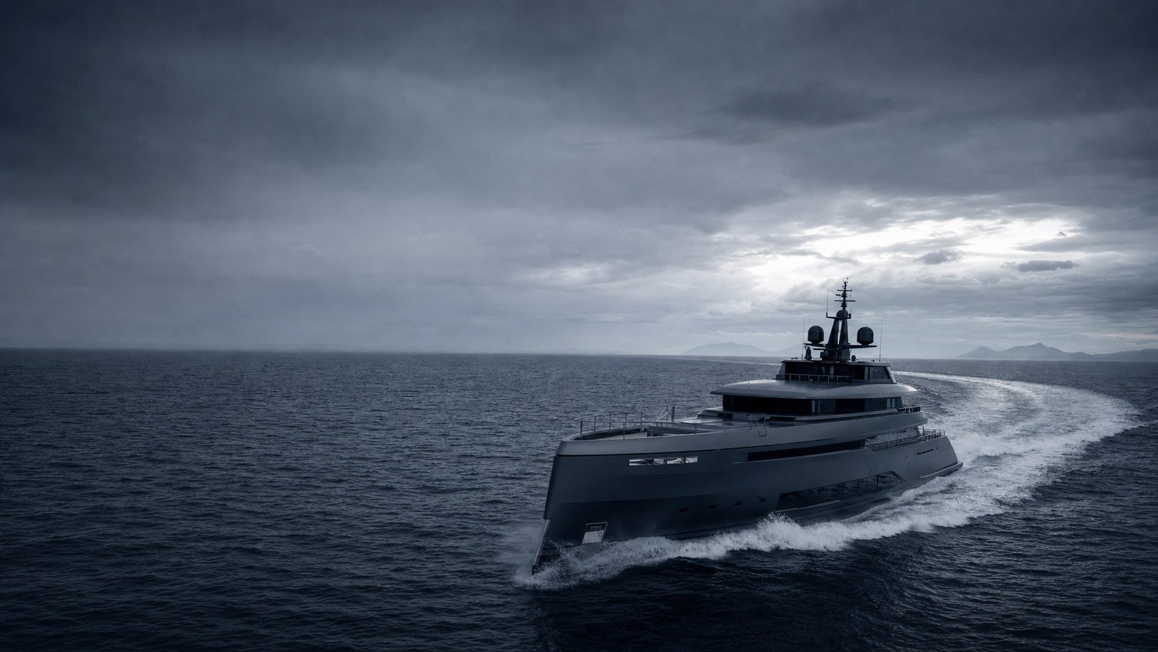 A dark-hulled superyacht running at speed across open water under a moody, monochrome dusk sky